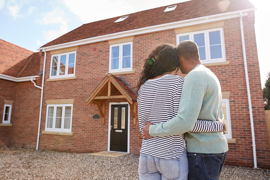 Personal Insurance - Young Couple Standing Outside Looking at Their New Two Story Home
